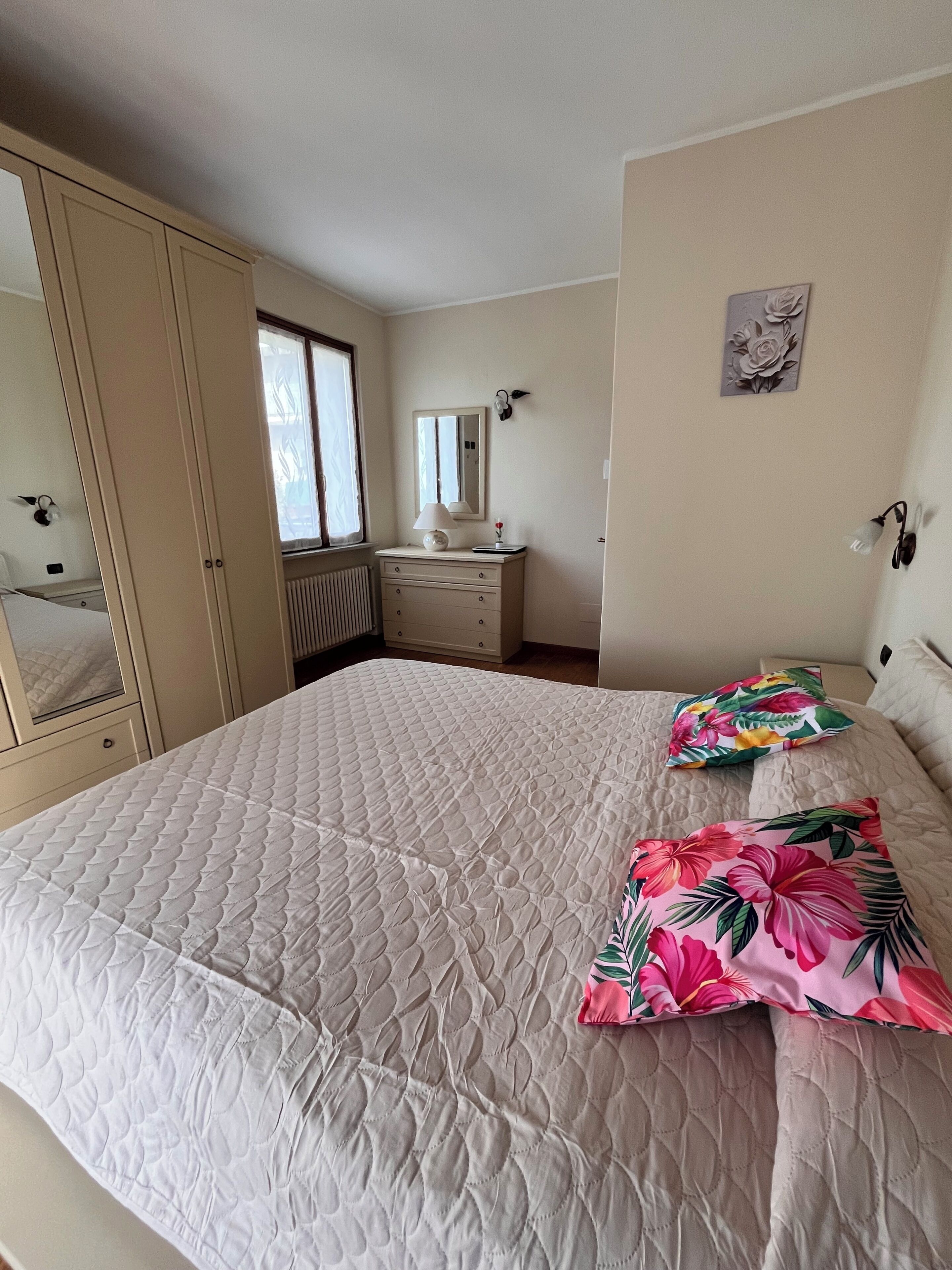Une chambre à coucher avec un grand lit, une commode, un miroir et une fenêtre.