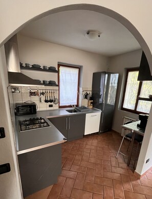 Een kleine keuken met een gasfornuis, een spoelbak en een koelkast.