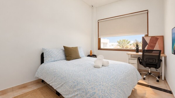 A bedroom with a bed, a desk, and a chair.