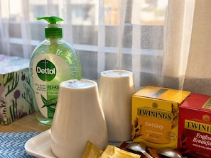 A table with a bottle of Dettol, two white cups, a box of Twinings Earl Grey tea, and a box of Twinings English Breakfast tea.