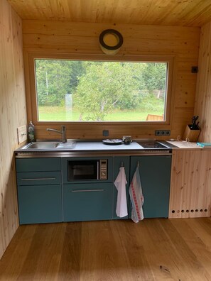 A compact kitchen with a large window, wooden cabinets, and a built-in oven.