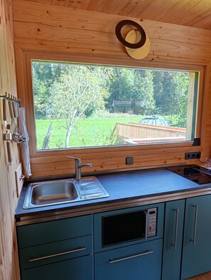 A kitchen with a large window, wooden cabinets, a stainless steel sink, and a built-in oven.