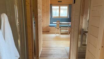 Ein Innenbereich mit Holzboden und -wänden, eine Bank und ein Tisch sind in der Ferne zu sehen.