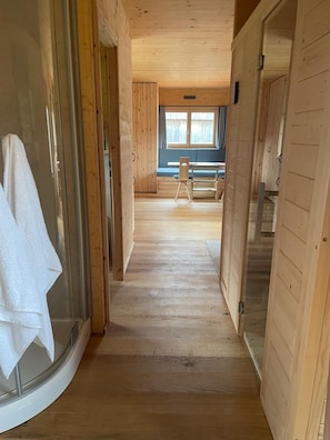 A wooden interior hallway with a bench and a table in the distance.