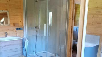 A wooden interior with a glass-enclosed shower, a sink, and a mirror.