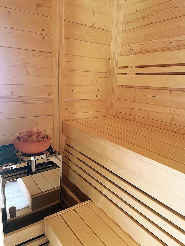 A sauna room with wooden walls and a bench.
