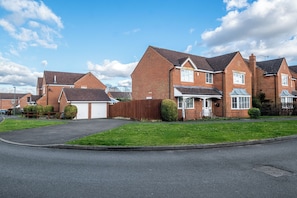 A residential street with brick houses, a clear sky, and a well-maintained lawn. - Spacious 5 Bed 2 Bath House • Driveway Parking • Near NEC • Solihull • Airport (Balsall Common)