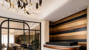 Zona de recepción de hotel con diseño moderno, que incluye un mostrador de recepción, un área de registro y un amplio ventanal con vista al comedor.