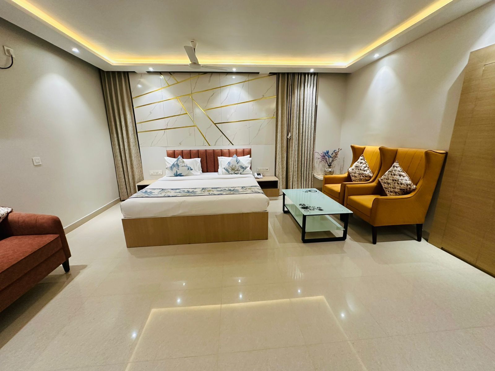 A modern hotel room with a bed, a sofa, a coffee table, and a decorative wall.