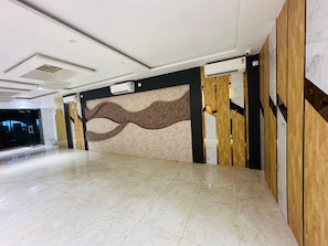 A spacious lobby with a marble floor, a modern ceiling design, and a decorative wall panel. - HOTEL ADITYA MARINE GARDEN (Patna)