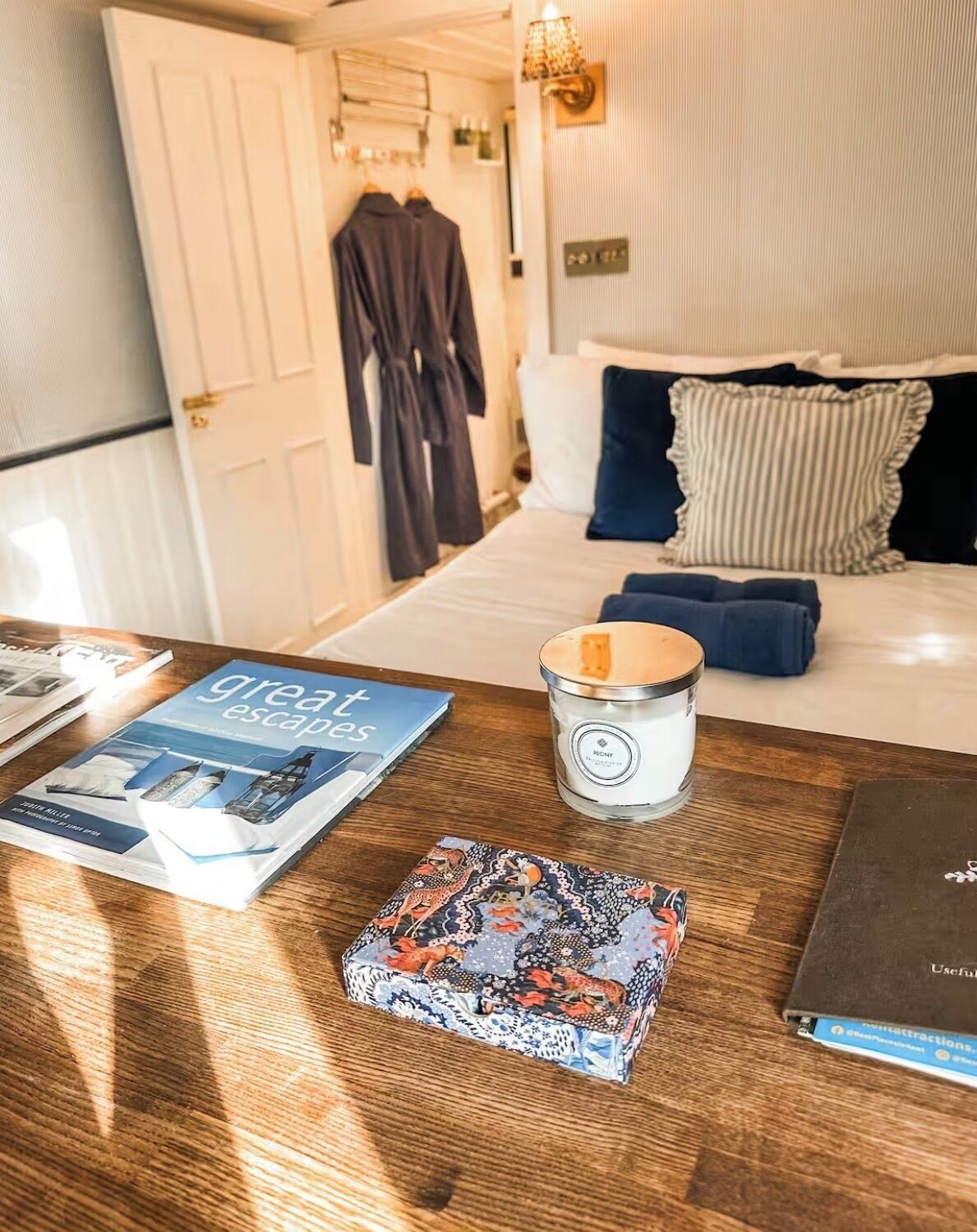 Een hotelkamer met een bed, een nachtkastje met een kaars, een boek en een decoratieve doos.