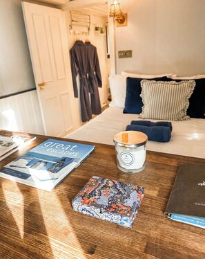 Een hotelkamer met een bed, een nachtkastje met een kaars, een boek en een decoratieve doos.