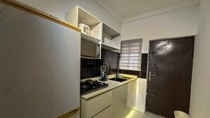 Una cucina compatta con piano cottura integrato, lavello e porta scura.