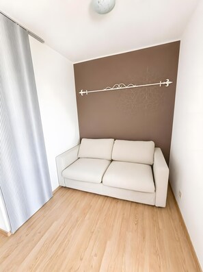 A room with a white sofa, a brown accent wall, and a wooden floor.
