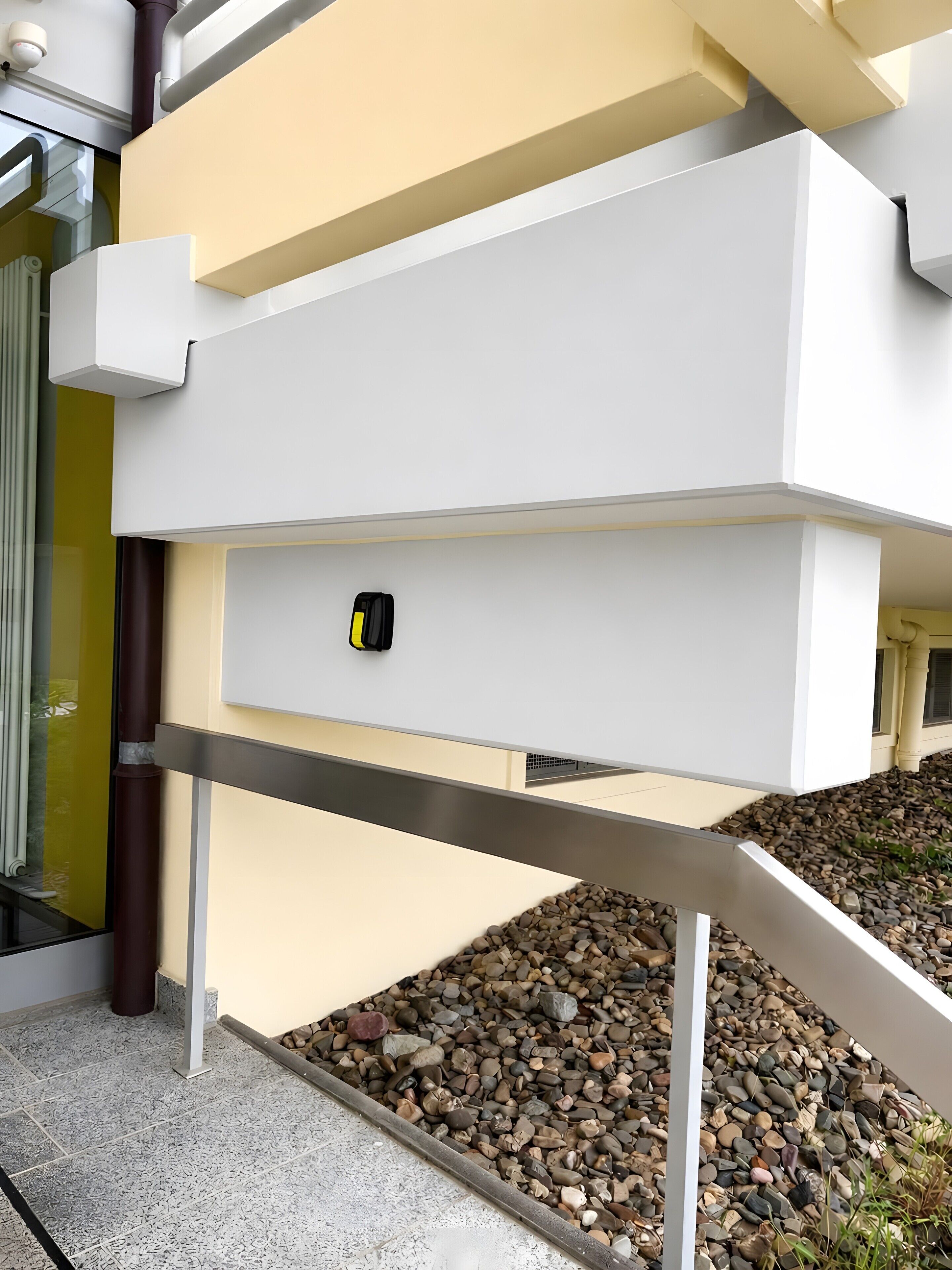 Un edificio moderno con tetto piatto, facciata bianca e ringhiera in metallo.