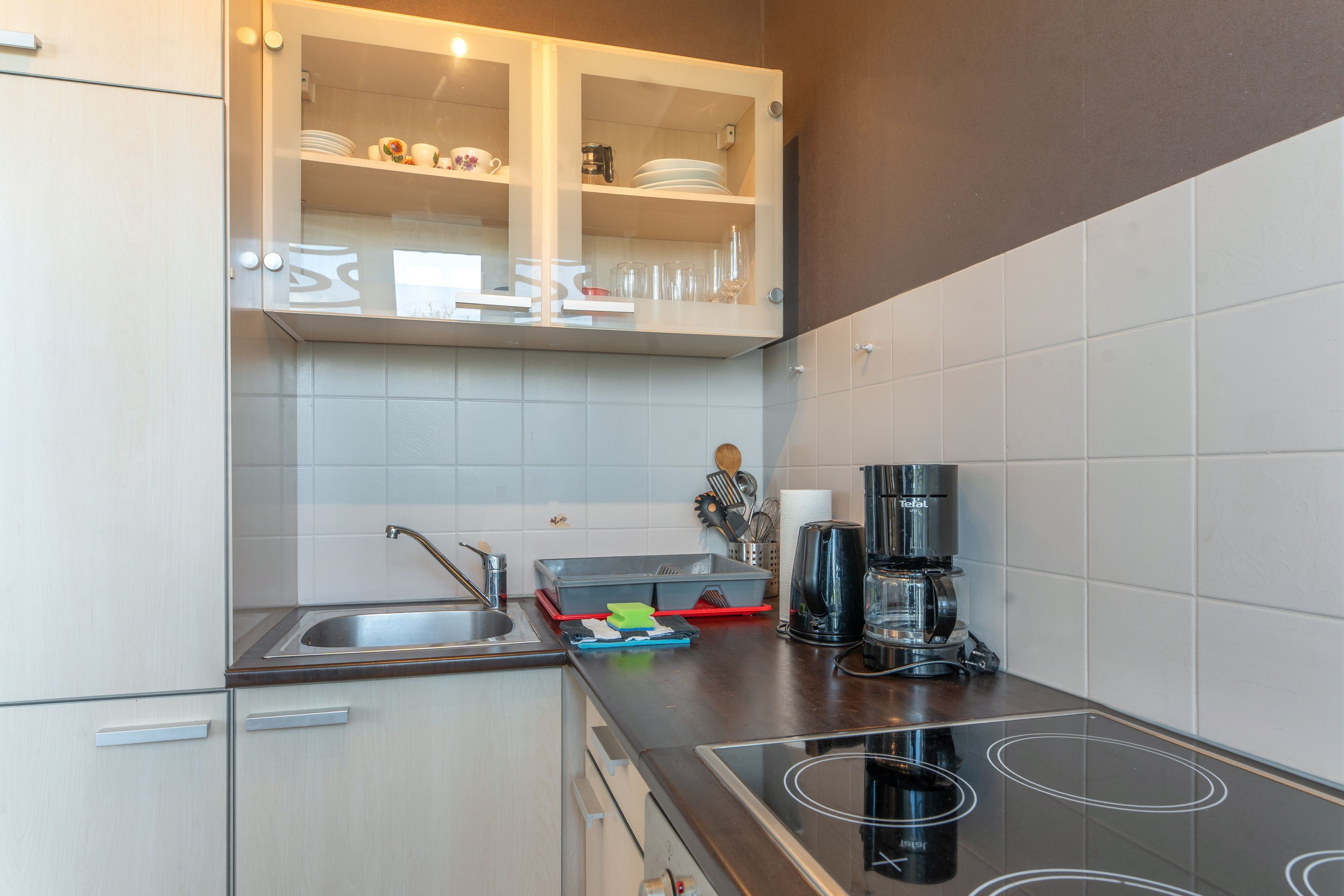 A modern kitchen with a built-in stove, a coffee maker, and a dish rack.