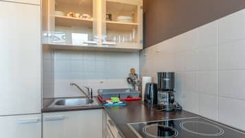 A modern kitchen with a built-in stove, a coffee maker, and a dish rack.