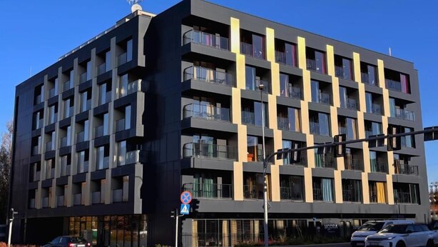 A multi-story building with balconies, a pedestrian crossing, and a no parking sign.