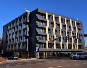 A multi-story building with balconies, a parking area, and a clear sky. - K52 Apartments (Wrocław)