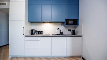 Una cocina moderna con armarios blancos, encimera negra y microondas integrado.