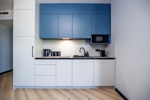 A modern kitchen with white cabinets, a black countertop, and a built-in microwave. - K52 Apartments (Wrocław)