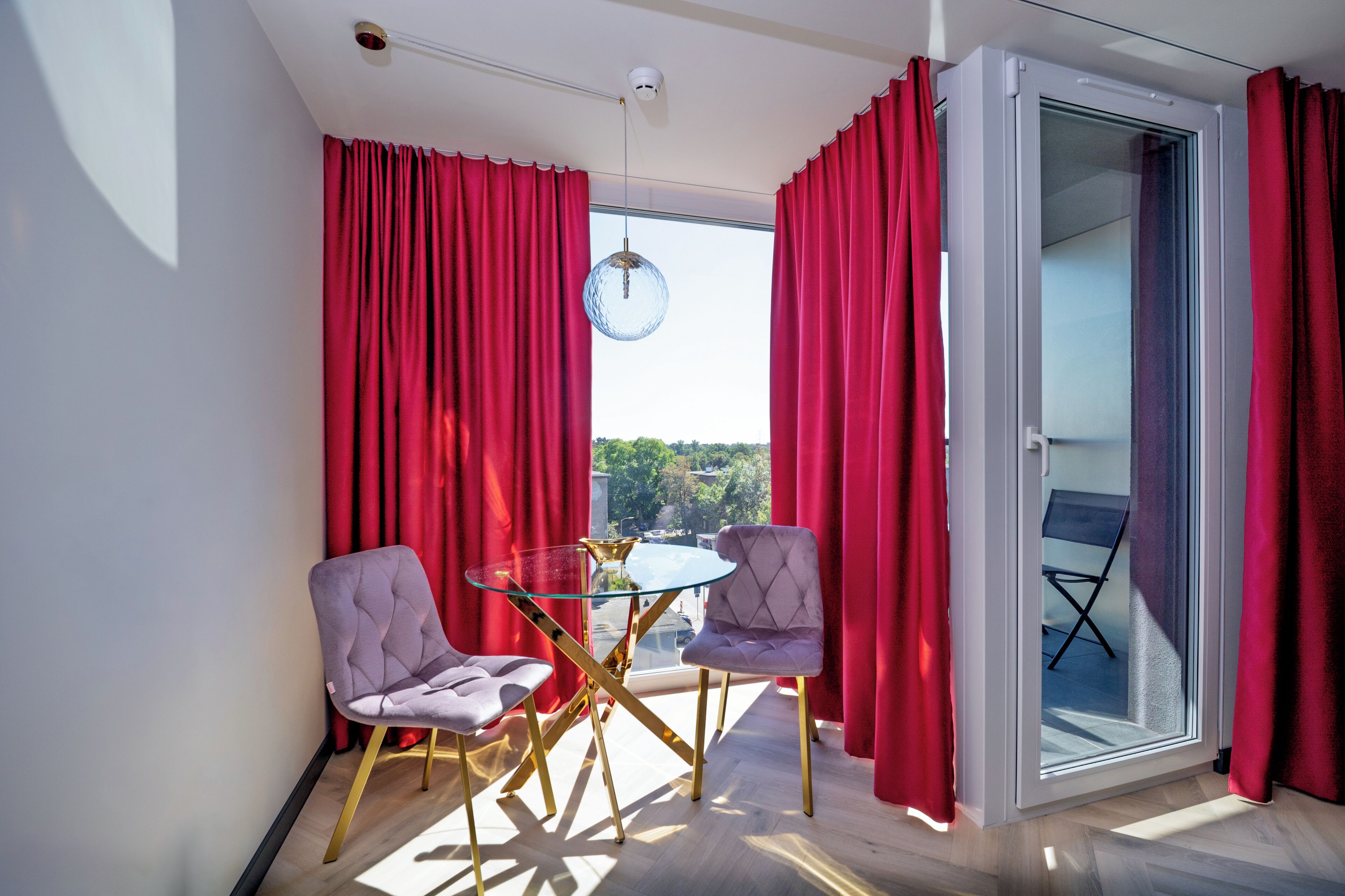 A modern room with a glass table, two chairs, and a view through a sliding glass door.