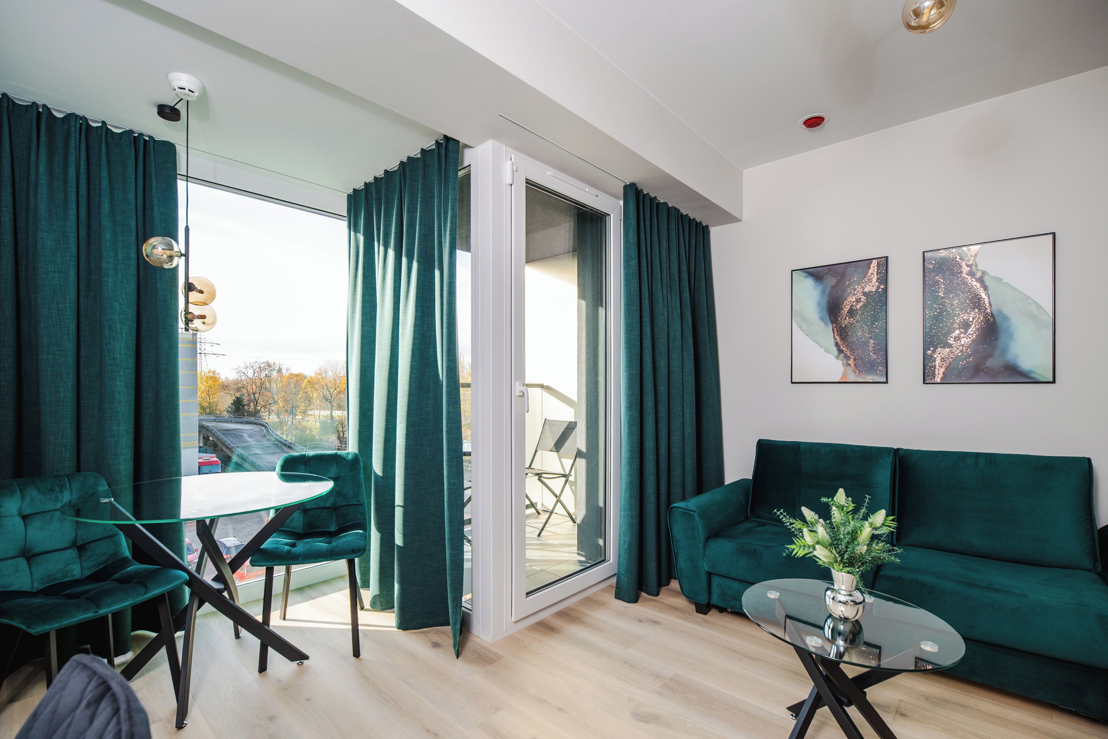 Una sala de estar moderna con un sofá verde, una mesa de centro de vidrio y un comedor con una mesa y sillas.