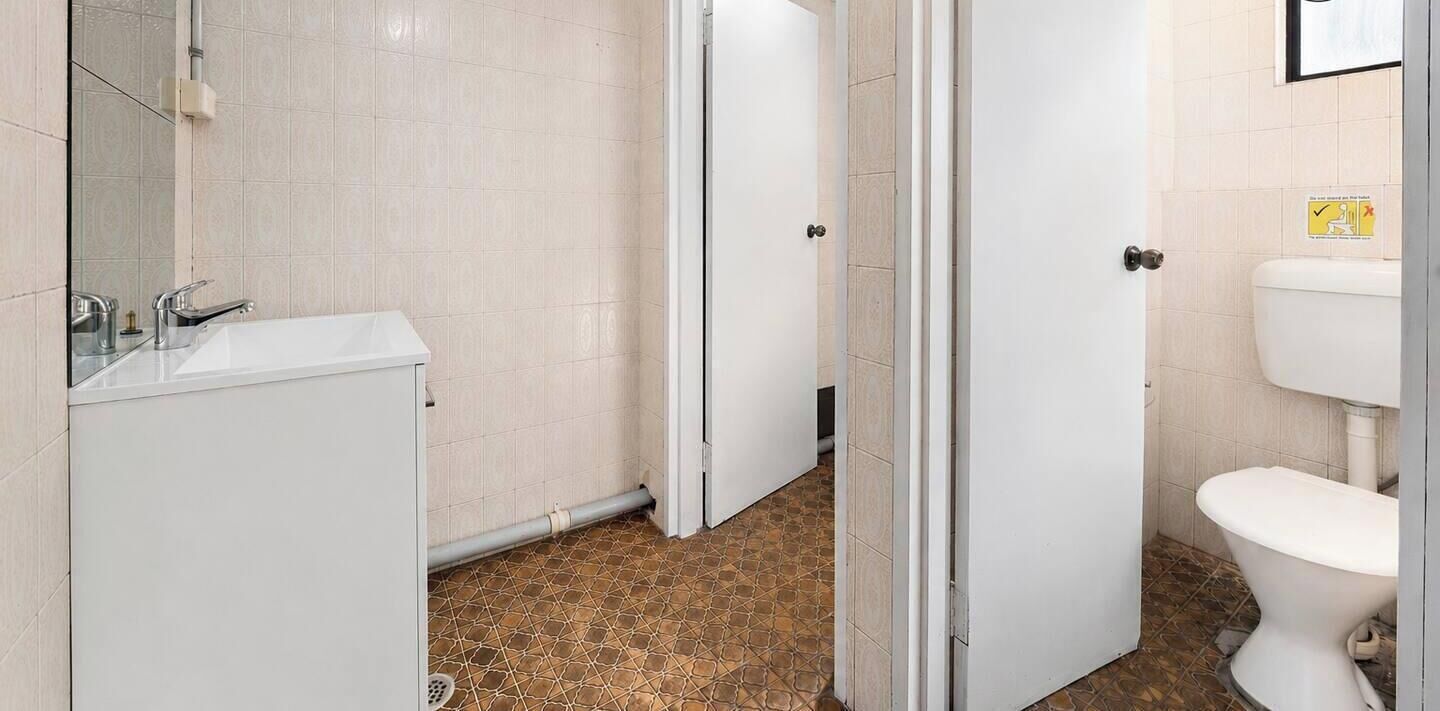 A bathroom with a white sink, mirror, and tiled walls.
