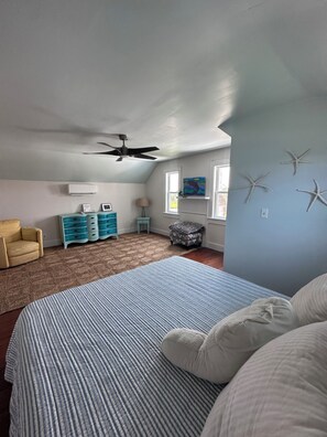 A bedroom with a bed, a chair, a dresser, a nightstand, and a ceiling fan.