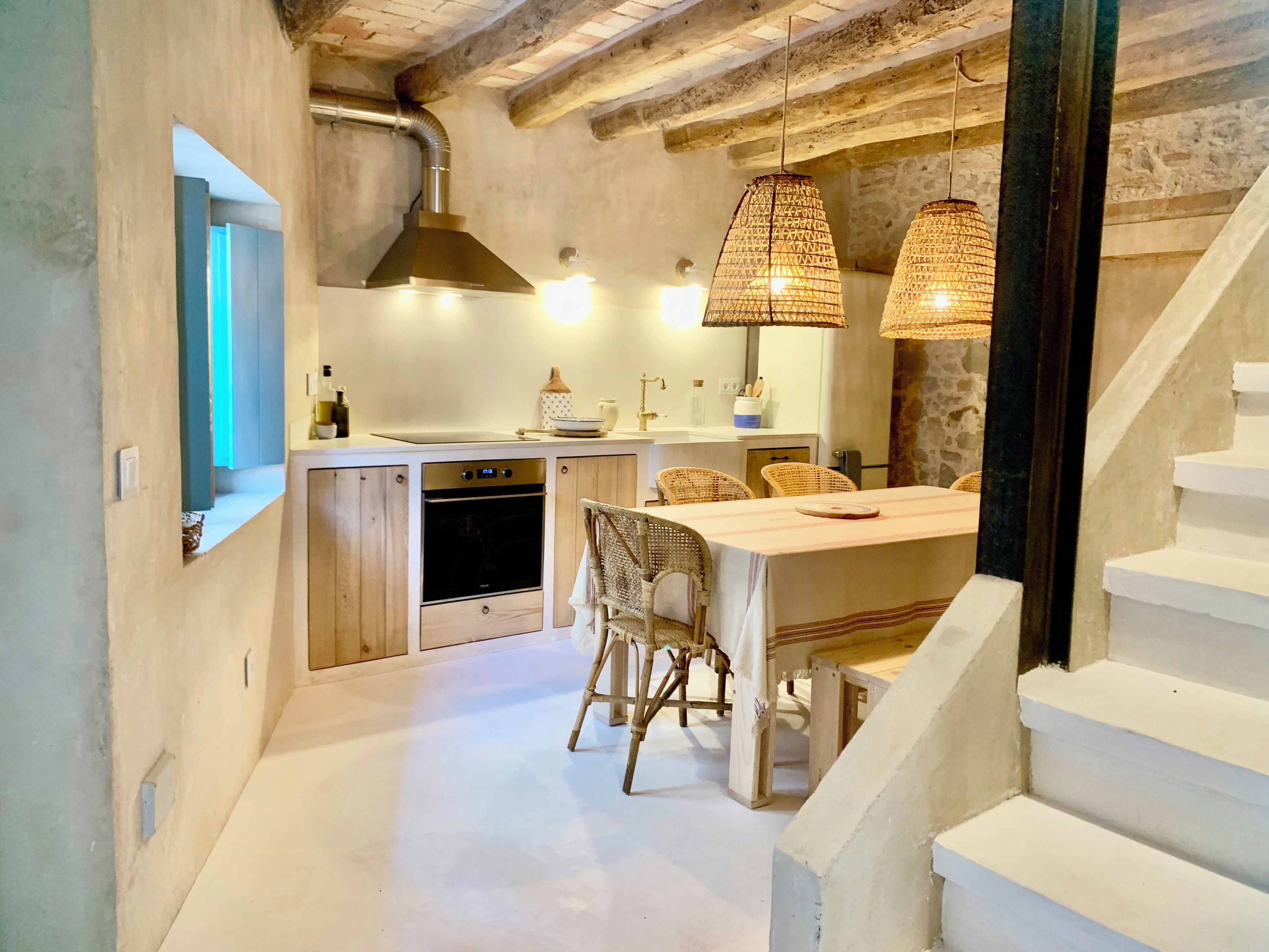 A kitchen with wooden cabinets, a built-in oven, and a dining area with wicker chairs.