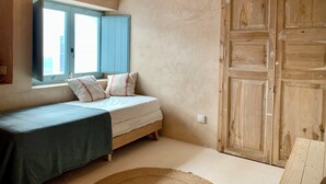 A bedroom with a bed, a window with blue shutters, a wooden wardrobe, and a hanging light fixture. - Restored fisherman's house in l'Escala (L'Escala)