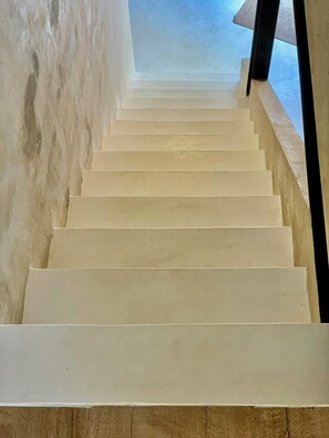 A staircase with a plain wall on one side and a window on the other. - Restored fisherman's house in l'Escala (L'Escala)