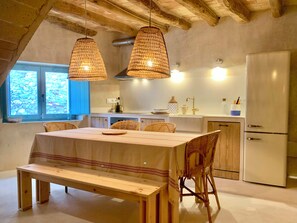 A kitchen with a dining table, chairs, and a bench. There are hanging lights and a refrigerator. - Restored fisherman's house in l'Escala (L'Escala)