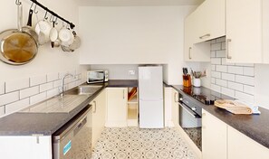 A compact kitchen with white cabinets, a stainless steel sink, a microwave, and a refrigerator. - The Twinflower - townhouse in the heart of Grantown on Spey (Grantown-on-Spey)