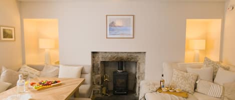 Una sala de estar acogedora con chimenea, una mesa de comedor con comida y un sofá.