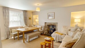 A cozy living room with a fireplace, a dining table, and comfortable seating. - The Twinflower - townhouse in the heart of Grantown on Spey (Grantown-on-Spey)