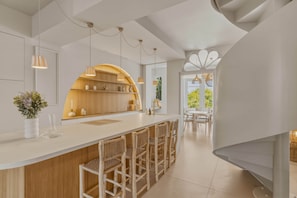 Eine moderne Küche mit Barbereich, Holzschränken und Blick auf einen Essbereich.