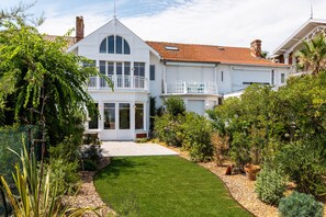 Ein zweigeschossiges Haus mit einer großen Veranda, einem Balkon und einem gepflegten Garten.