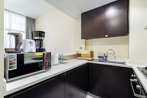A compact kitchen with a coffee maker, a microwave, a toaster, a sink, and a cabinet. - Modern 1BR in Merano Tower (Dubai)