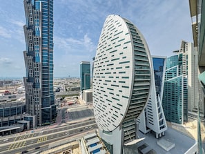 A modern cityscape with prominent curved skyscrapers and a busy road below. - Modern 1BR in Merano Tower (Dubai)