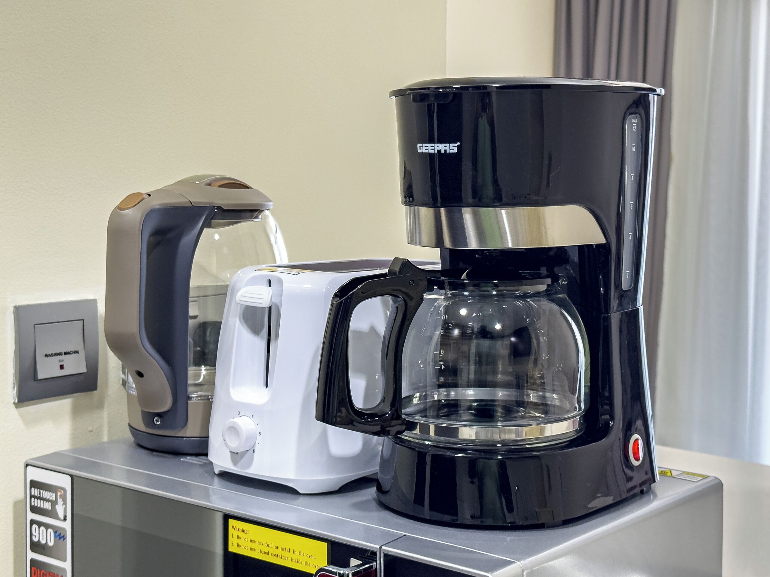 Une machine à café, un grille-pain et un four à micro-ondes sont posés sur un plan de travail.