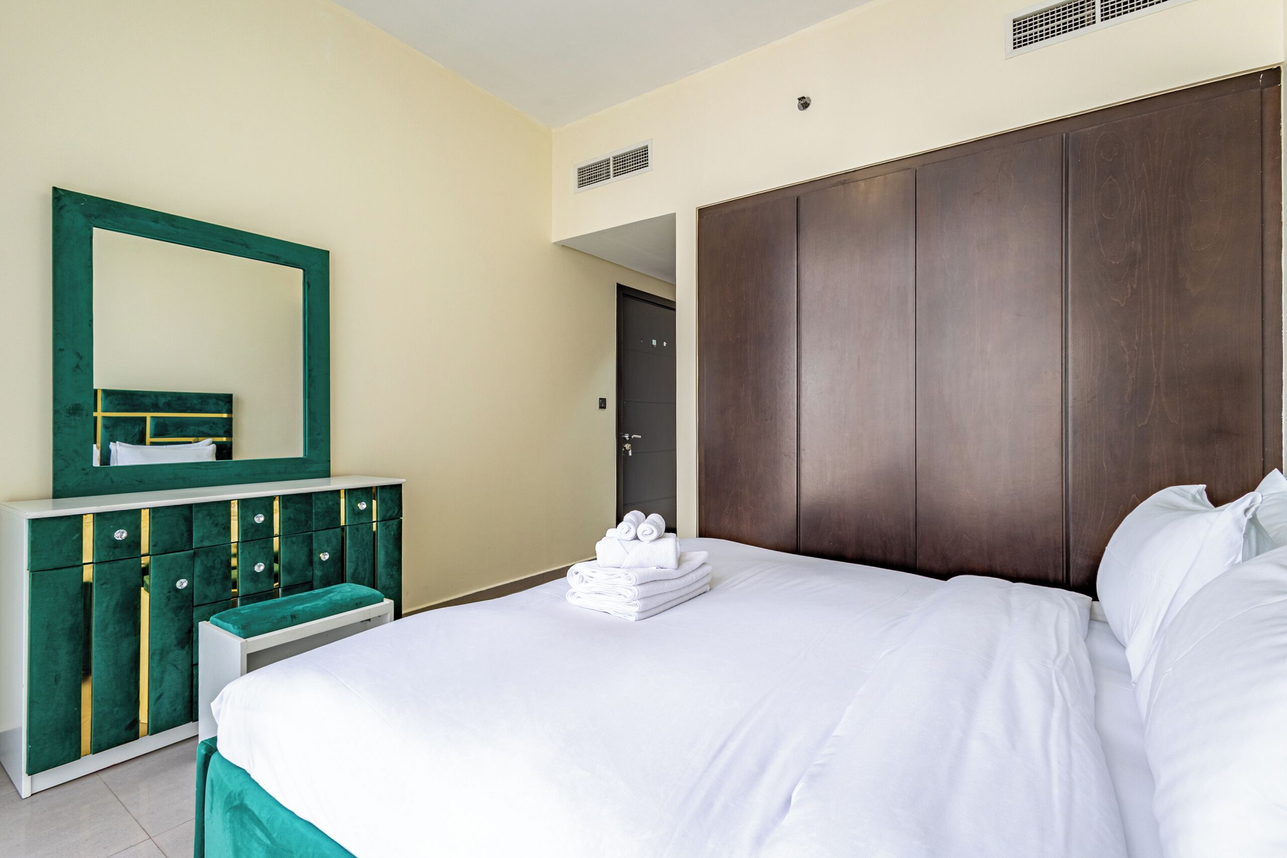Quarto de hotel com cama, penteadeira com espelho e armário.