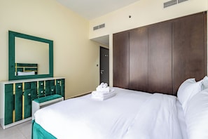 A hotel room with a bed, a vanity with a mirror, and a wardrobe. - Modern 1BR in Merano Tower (Dubai)