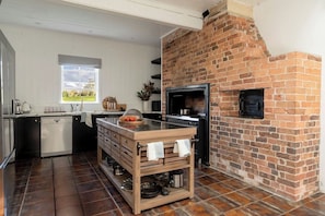 A kitchen with a brick oven, wooden cabinetry, and a window overlooking a garden. - 'Glenworth House' - Heritage Berry Mountain Estate (Berry Mountain)