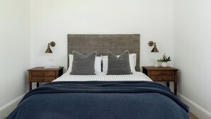 Ein Schlafzimmer mit einem Bett, zwei Nachttischen, einem Kopfteil und Nachttischlampen.
