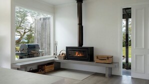 Ein modernes Wohnzimmer mit eingebautem Kamin, einem großen Fenster und einer Bank mit Körben.