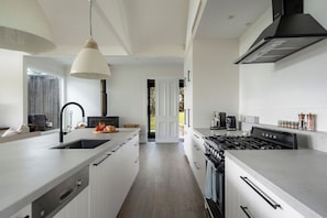A modern kitchen with a central island, a stove, and a sink. - 'The Cottage' at Glenworth Estate (Berry Mountain)