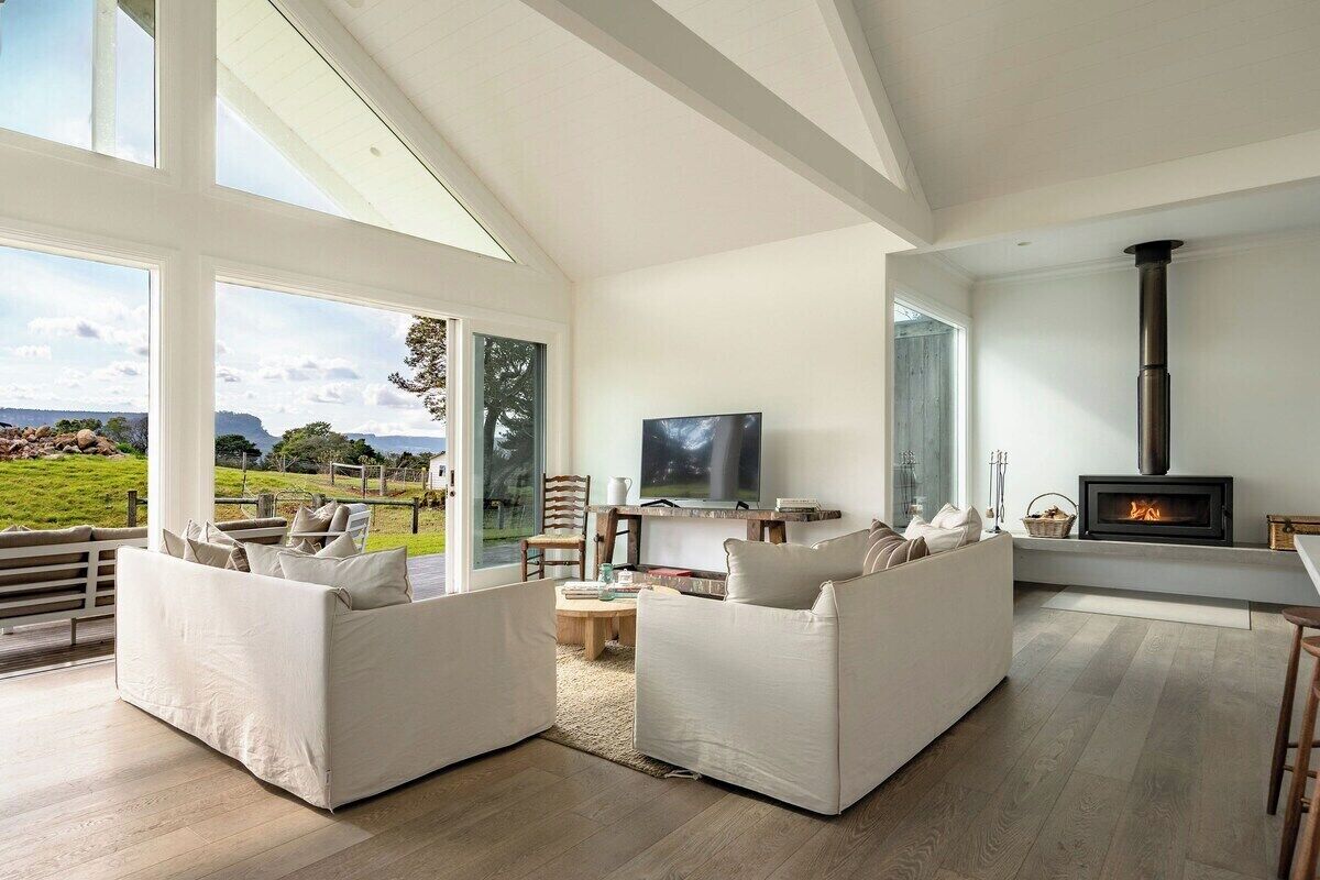 A spacious living room with a fireplace, large windows, and a comfortable seating area.
