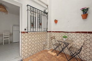A small outdoor patio with a metal table and chairs, a white door, and patterned wall tiles. - ‘El Olivo 1’ Apartment with Private Terrace, Wi-Fi, and Air Conditioning (Málaga)