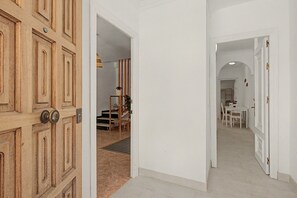 Ein Flur mit einer Holztür, ein Essbereich mit Tisch und Stühlen sowie eine Treppe, die zu einer weiteren Ebene führt.